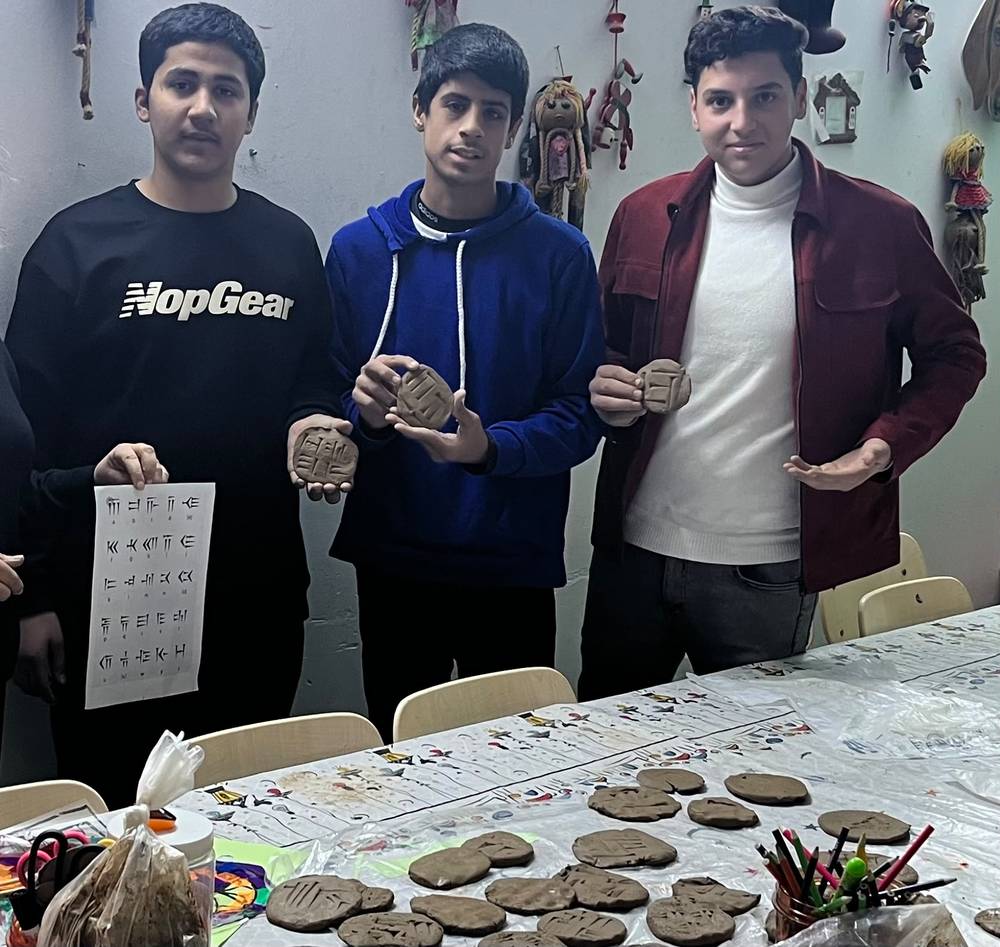 Boys holding clay tablets with cuneiform writing