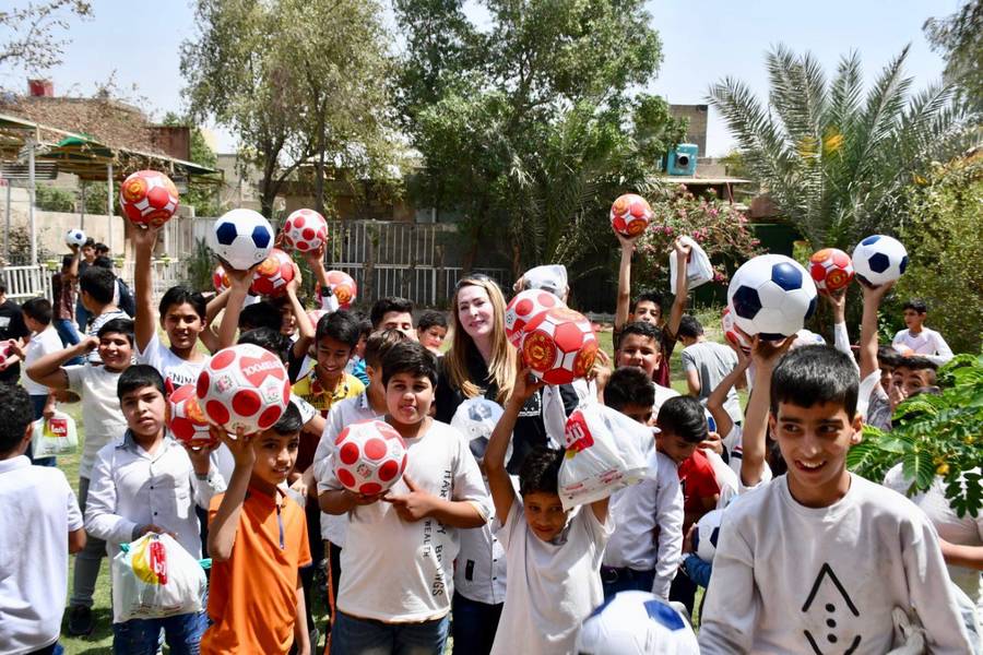 Boys holding up new footballs in the school playground